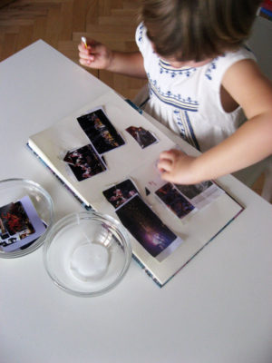 Dieťa lepí s lepidlom v miske s paličkou výstrižky z magazínu na papier