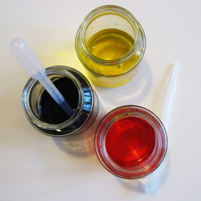 Modré, červené a žlté potravinárske farbivo v pohárikoch od výživy s pipetkami